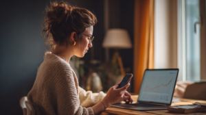 a woman watching her traffic climb on the laptop, then reaching for a phone